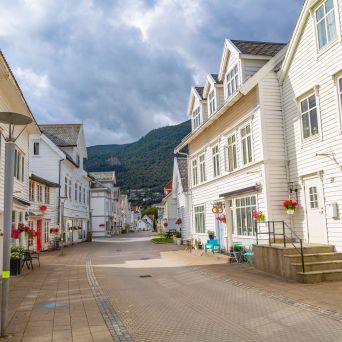 Quiet street with white wooden houses and mountains in the background.
